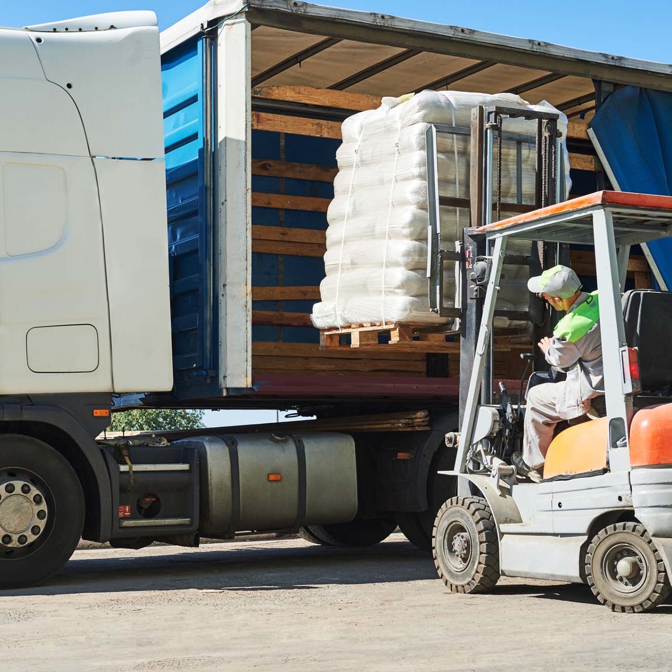 Forklift loading a pallet of products onto the side of a 40 foot truck